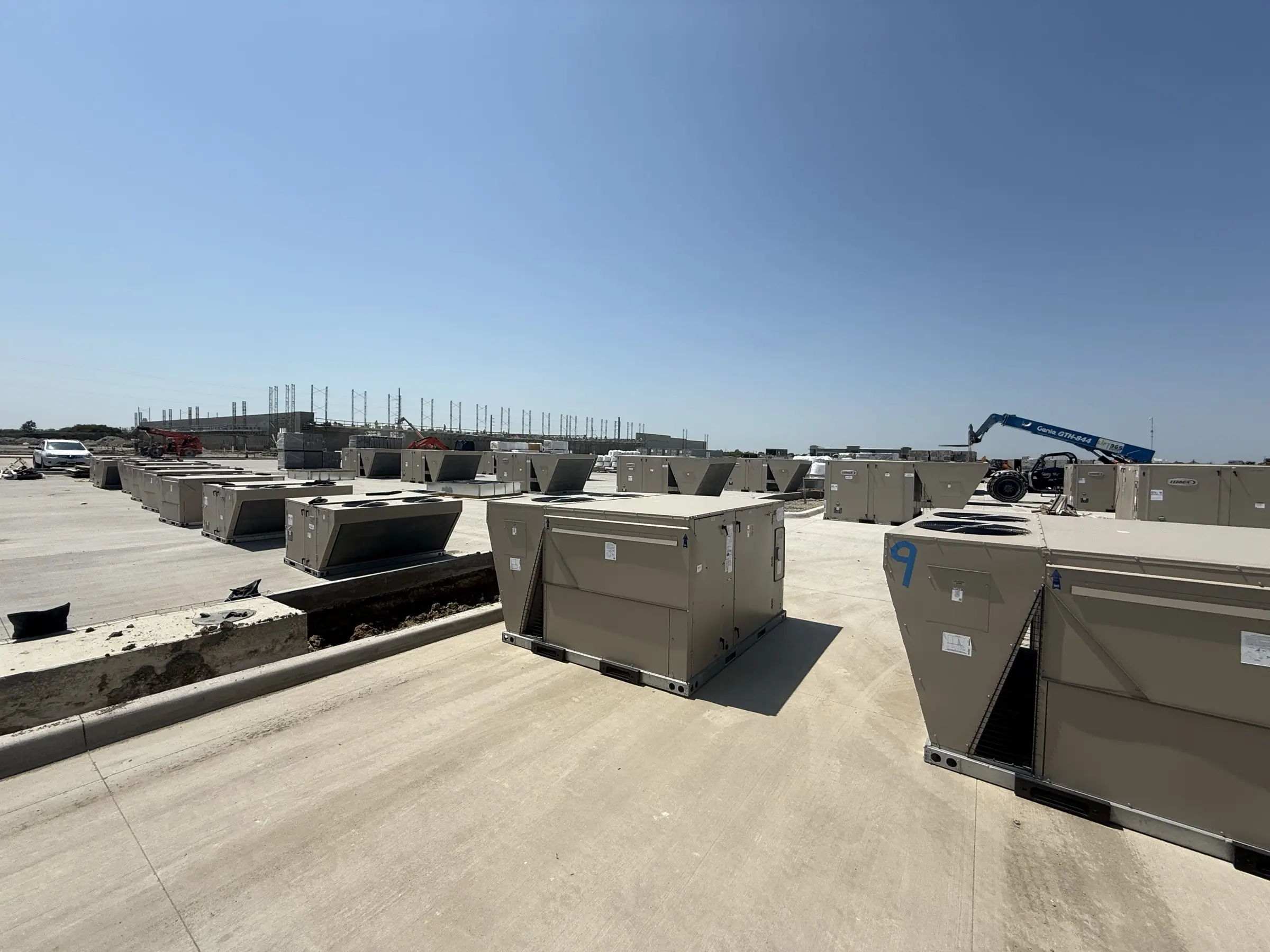 New rooftop package units staged across a commercial roof ahead of installation